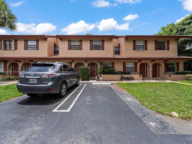 10942 W Sample Rd Unit E1, Coral Springs, FL 33065 - view of front facade with stucco siding, uncovered parking, and a front lawn