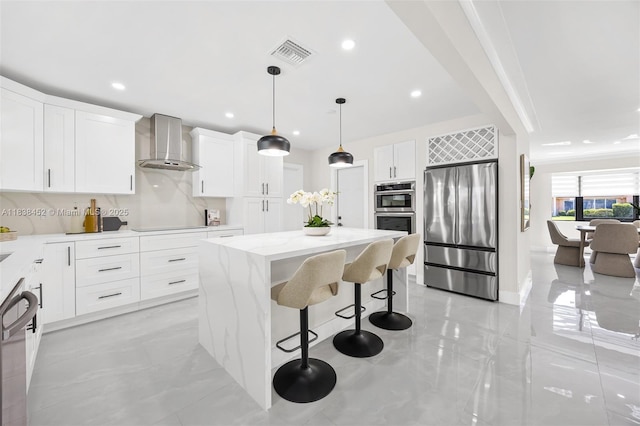 220 SW 75th Ter, Plantation, FL 33317 - kitchen featuring appliances with stainless steel finishes, wall chimney exhaust hood, a kitchen island, a breakfast bar area, and light stone countertops