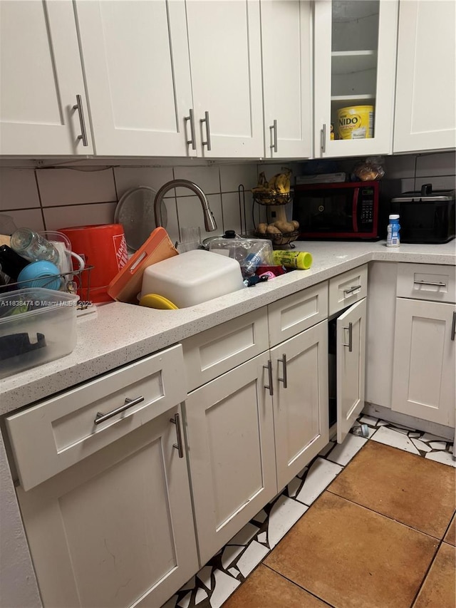 3610 NW 21st St Unit 413, Lauderdale Lakes, FL 33311 - kitchen featuring white cabinetry, light tile patterned flooring, glass insert cabinets, and tasteful backsplash