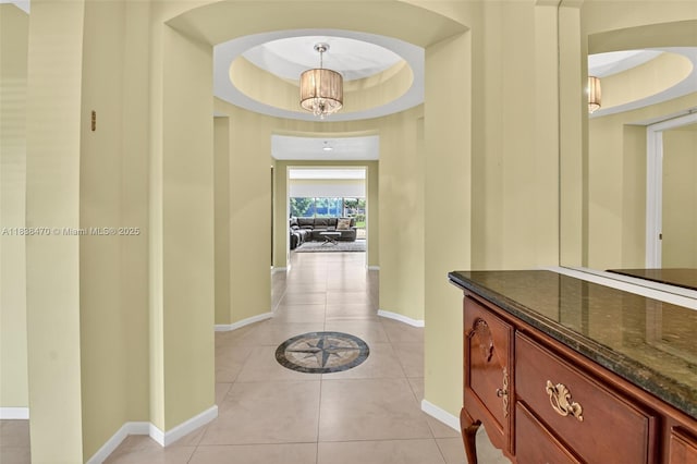 5938 Crystal Shores Dr Unit 103, Boynton Beach, FL 33437 - hallway featuring light tile patterned flooring, a raised ceiling, a chandelier, and arched walkways