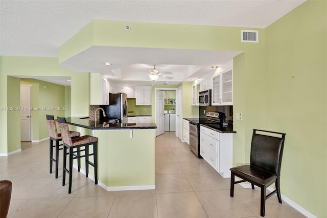 5938 Crystal Shores Dr Unit 103, Boynton Beach, FL 33437 - kitchen with appliances with stainless steel finishes, washer and clothes dryer, a peninsula, a breakfast bar area, and light tile patterned floors