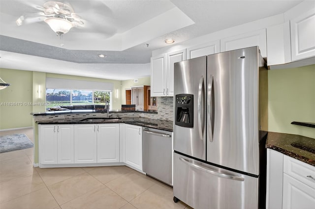 5938 Crystal Shores Dr Unit 103, Boynton Beach, FL 33437 - kitchen featuring appliances with stainless steel finishes, a peninsula, white cabinetry, dark stone counters, and a tray ceiling