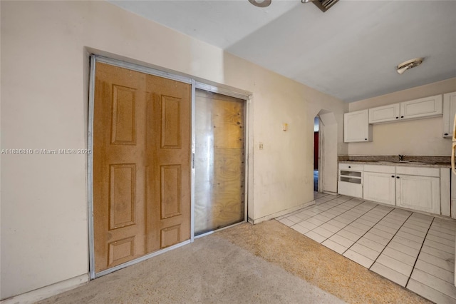 3300 NW 211th St, Miami Gardens, FL 33056 - kitchen featuring arched walkways, white cabinetry, and light tile patterned flooring