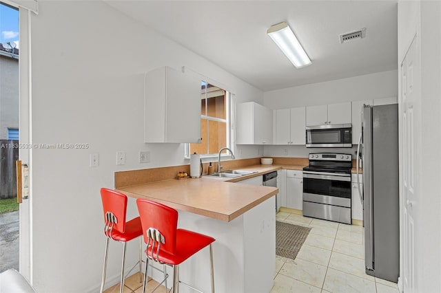 771 SE 2nd St, Homestead, FL 33030 - kitchen featuring appliances with stainless steel finishes, a peninsula, plenty of natural light, and white cabinetry