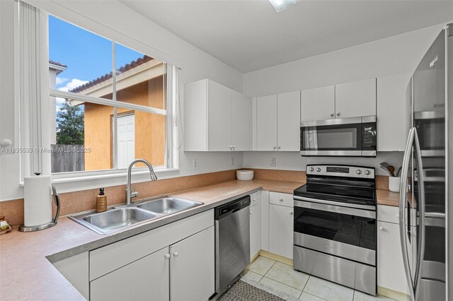 771 SE 2nd St, Homestead, FL 33030 - kitchen with stainless steel appliances, light countertops, white cabinets, and light tile patterned floors