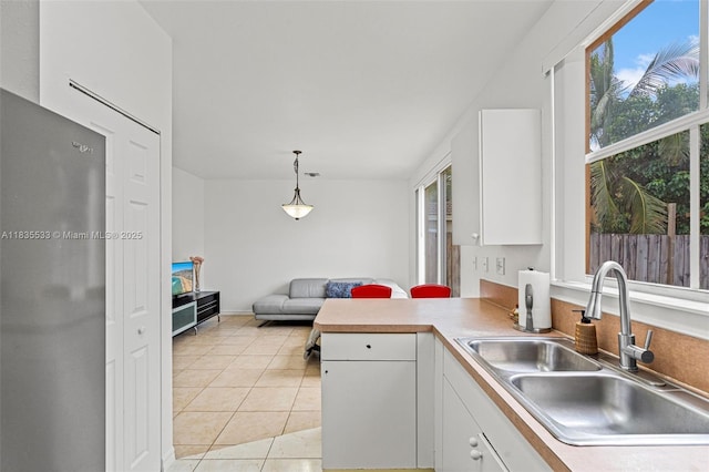 771 SE 2nd St, Homestead, FL 33030 - kitchen with a peninsula, white cabinets, light tile patterned floors, decorative light fixtures, and light countertops