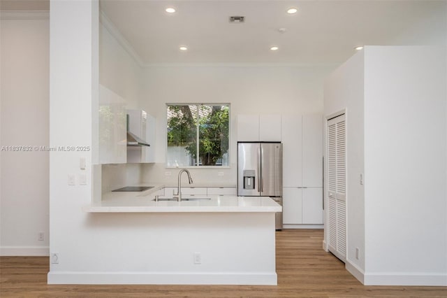 2664 Edgewater Dr, Weston, FL 33332 - kitchen featuring stainless steel fridge with ice dispenser, a peninsula, light countertops, light wood-style floors, and ornamental molding
