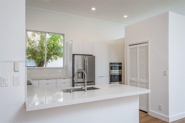2664 Edgewater Dr, Weston, FL 33332 - kitchen with stainless steel appliances, modern cabinets, light wood-style flooring, a peninsula, and ornamental molding