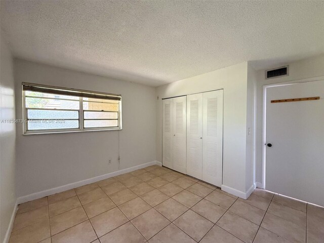 8650 SW 109th Ave Unit 3-112, Miami, FL 33173 - unfurnished bedroom with a closet, a textured ceiling, and light tile patterned floors