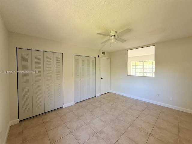 8650 SW 109th Ave Unit 3-112, Miami, FL 33173 - unfurnished bedroom featuring two closets, light tile patterned floors, a textured ceiling, and ceiling fan