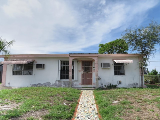 525 NW 16th St, Pompano Beach, FL 33060 - view of front facade with stucco siding, a wall mounted AC, and a front lawn