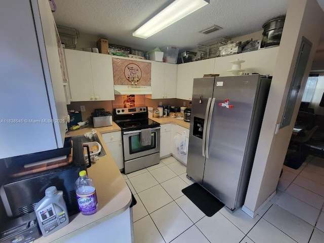 1640 NE 5th St, Homestead, FL 33033 - kitchen with stainless steel appliances, under cabinet range hood, light countertops, a textured ceiling, and light tile patterned floors