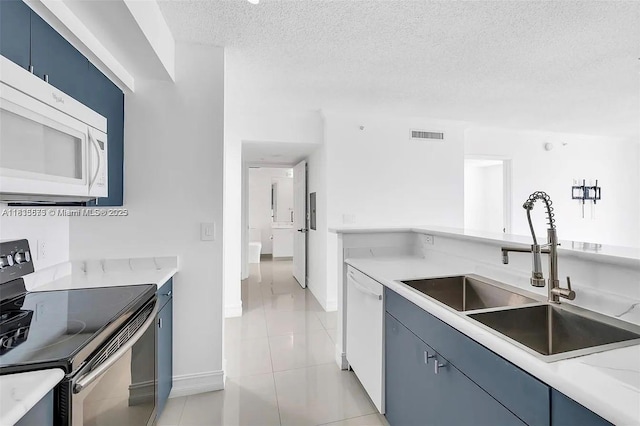 1919 Van Buren St Unit 505A, Hollywood, FL 33020 - kitchen with white appliances, blue cabinets, a textured ceiling, light countertops, and light tile patterned flooring