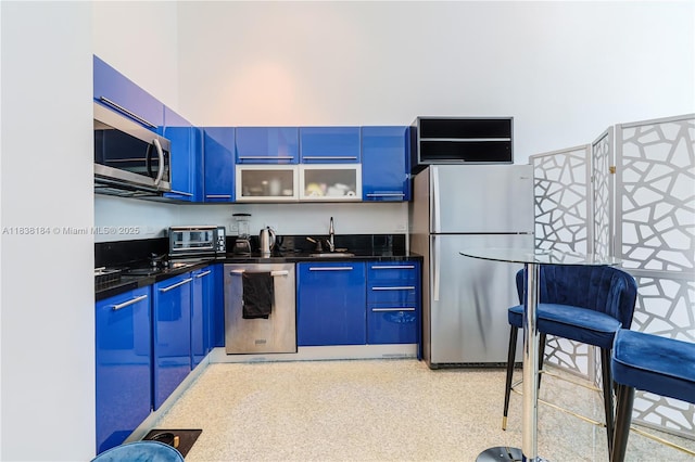 253 NE 2nd St Unit 213, Miami, FL 33132 - kitchen with stainless steel appliances, dark countertops, blue cabinetry, and glass insert cabinets