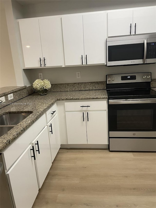 11605 NW 89th St Unit 112, Doral, FL 33178 - kitchen featuring appliances with stainless steel finishes, white cabinets, light wood finished floors, and stone countertops