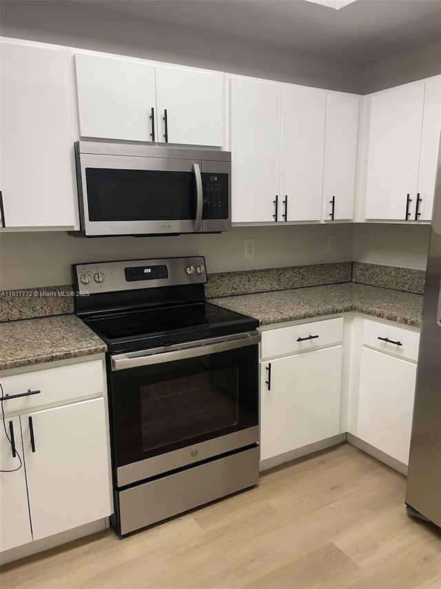 11605 NW 89th St Unit 112, Doral, FL 33178 - kitchen with appliances with stainless steel finishes, light wood-style flooring, white cabinetry, and stone countertops