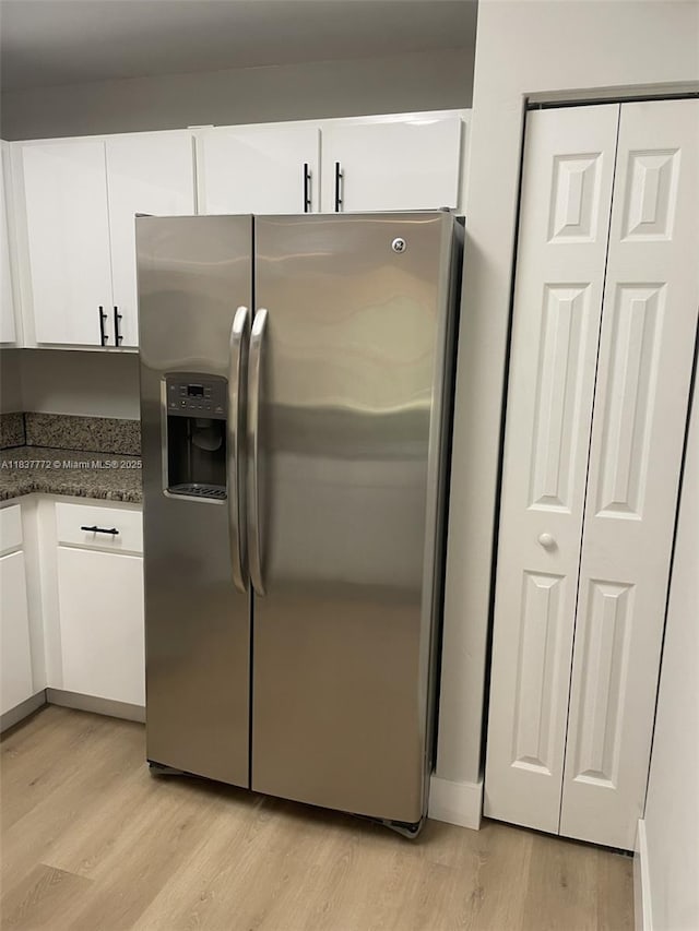11605 NW 89th St Unit 112, Doral, FL 33178 - kitchen with stainless steel refrigerator with ice dispenser, white cabinets, light wood-style flooring, and dark stone countertops