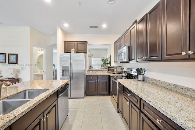 2851 W Prospect Rd Unit 1306, Tamarac, FL 33309 - kitchen with appliances with stainless steel finishes, dark brown cabinets, light tile patterned floors, light stone counters, and recessed lighting