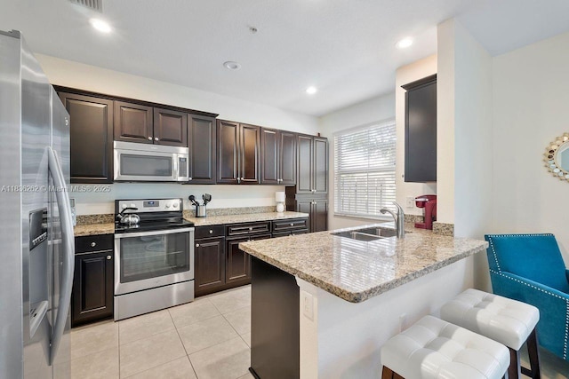 2851 W Prospect Rd Unit 1306, Tamarac, FL 33309 - kitchen with appliances with stainless steel finishes, a peninsula, dark brown cabinets, light tile patterned floors, and a breakfast bar