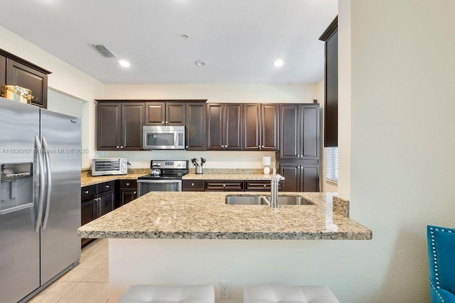 2851 W Prospect Rd Unit 1306, Tamarac, FL 33309 - kitchen featuring appliances with stainless steel finishes, dark brown cabinets, light stone counters, a peninsula, and light tile patterned floors