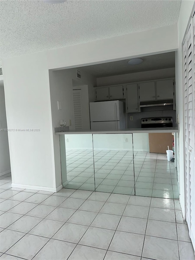 8897 Fontainebleau Blvd Unit 208, Miami, FL 33172 - kitchen featuring freestanding refrigerator, light tile patterned floors, under cabinet range hood, a textured ceiling, and gray cabinets