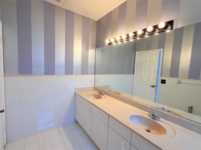 8973 NW 147th Ter, Miami Lakes, FL 33018 - bathroom featuring wallpapered walls, tile walls, double vanity, tile patterned floors, and wainscoting