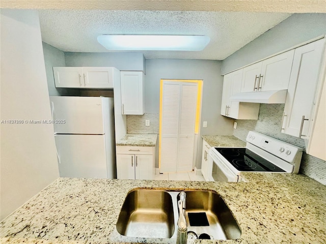 1231 SW 46th Ave Unit 507, Pompano Beach, FL 33069 - kitchen with white appliances, tasteful backsplash, white cabinets, under cabinet range hood, and light stone counters