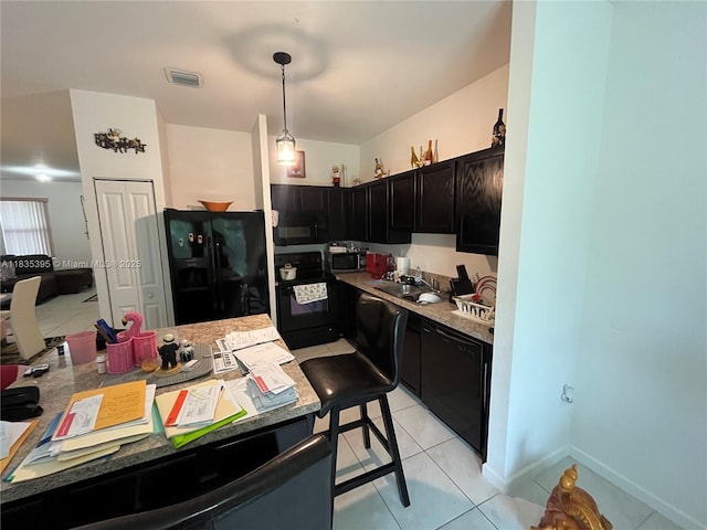 15924 SW 306th Ter, Homestead, FL 33033 - kitchen featuring black appliances, dark cabinetry, light tile patterned floors, decorative light fixtures, and light countertops