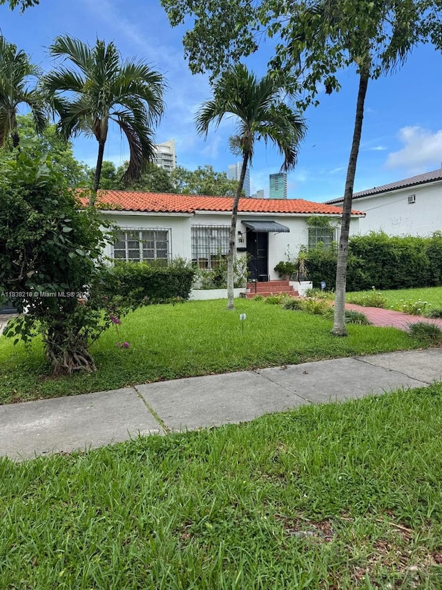 141 SW 20th Rd, Miami, FL 33129 - ranch-style house featuring a tiled roof, stucco siding, a front yard, and a chimney