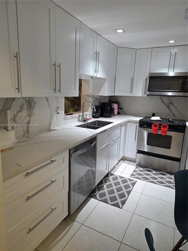 620 NE 12th Ave Unit 101, Hallandale Beach, FL 33009 - kitchen with stainless steel appliances, tasteful backsplash, light tile patterned floors, and white cabinets