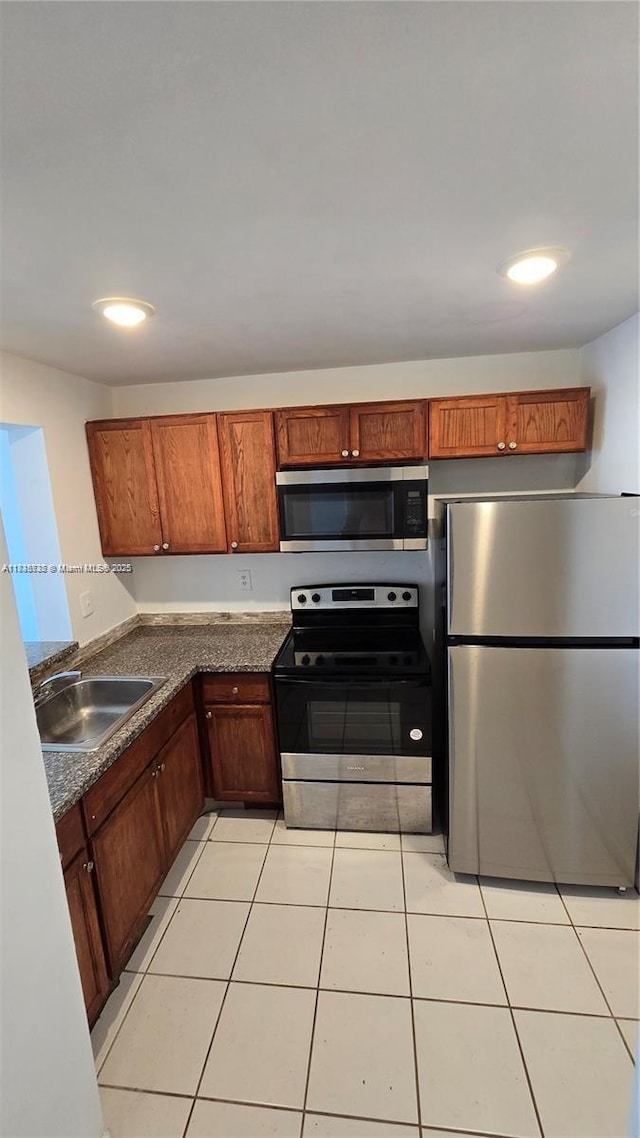 498 NW 165th St Rd Unit D-407, Miami, FL 33169 - kitchen with stainless steel appliances, dark countertops, light tile patterned floors, and brown cabinetry