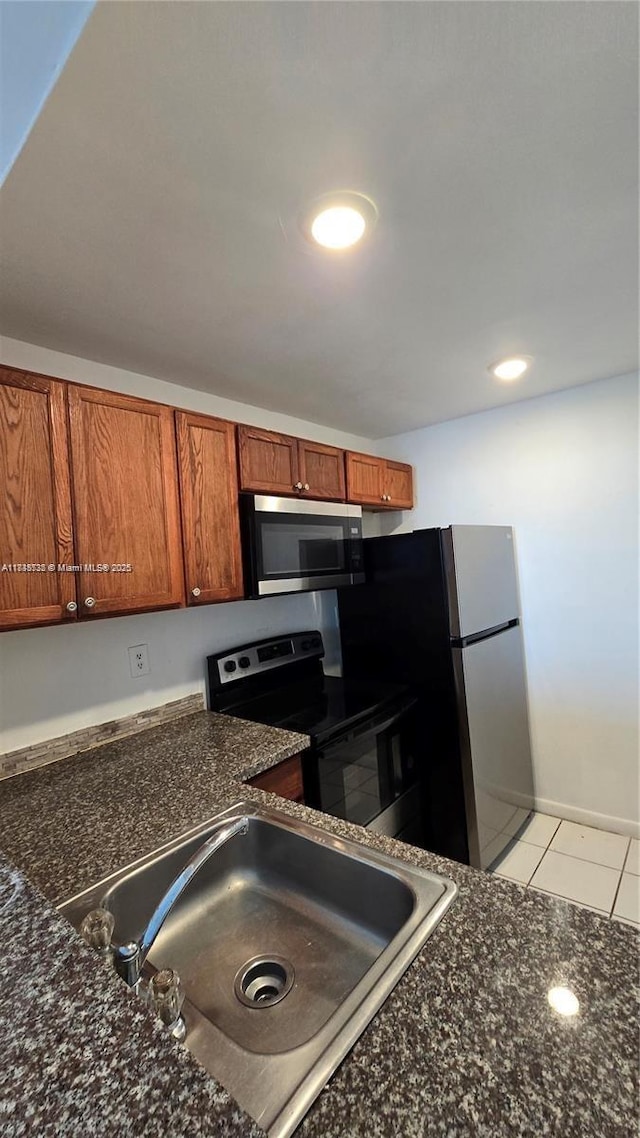 498 NW 165th St Rd Unit D-407, Miami, FL 33169 - kitchen with range with electric cooktop, stainless steel microwave, brown cabinets, light tile patterned floors, and dark stone countertops
