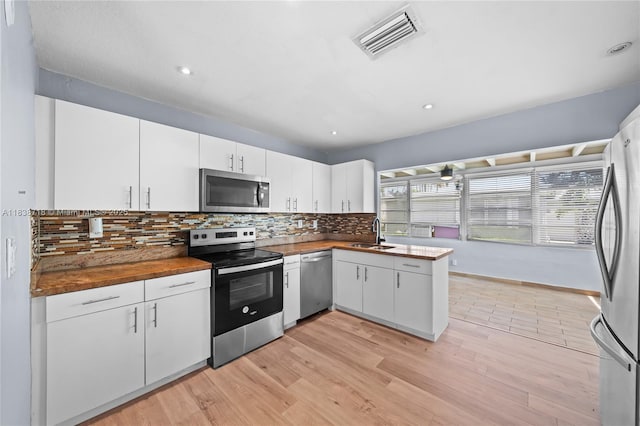 4938 NW 54th Ct, Tamarac, FL 33319 - kitchen with stainless steel appliances, butcher block counters, backsplash, white cabinets, and light wood-style flooring