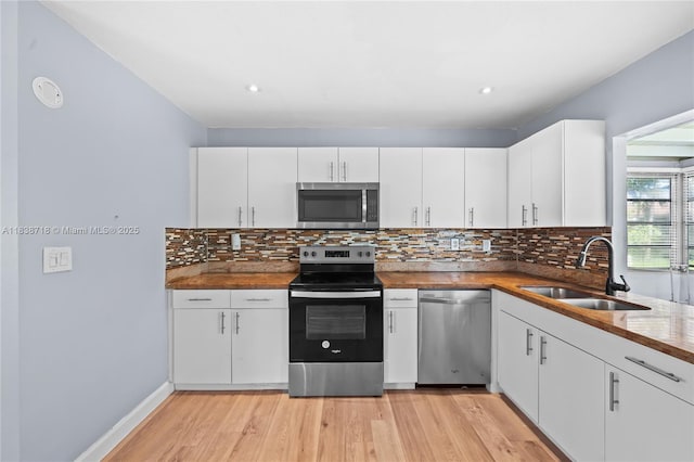 4938 NW 54th Ct, Tamarac, FL 33319 - kitchen with stainless steel appliances, light wood finished floors, decorative backsplash, white cabinetry, and wooden counters