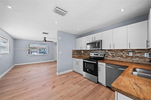 4938 NW 54th Ct, Tamarac, FL 33319 - kitchen featuring stainless steel appliances, decorative backsplash, light wood finished floors, white cabinets, and recessed lighting