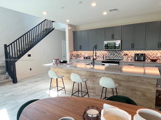 8813 Antarus Dr Unit 8813, Lake Worth, FL 33467 - kitchen featuring stainless steel microwave, electric range, decorative backsplash, a breakfast bar, and recessed lighting