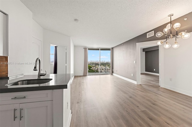 5077 NW 7th St Unit Ph15, Miami, FL 33126 - kitchen with a textured ceiling, dark countertops, open floor plan, light wood finished floors, and a chandelier