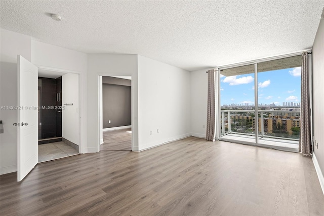 5077 NW 7th St Unit Ph15, Miami, FL 33126 - spare room with wood finished floors, a textured ceiling, and expansive windows