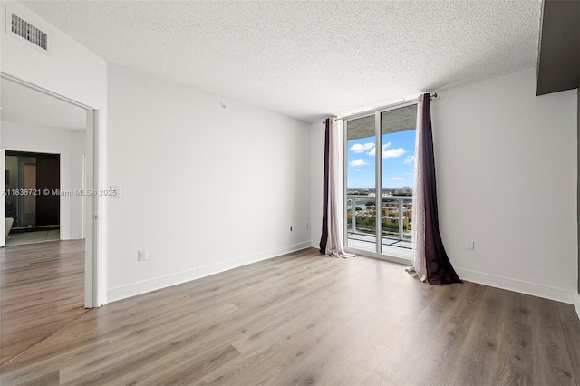 5077 NW 7th St Unit Ph15, Miami, FL 33126 - empty room with a textured ceiling, wood finished floors, and floor to ceiling windows