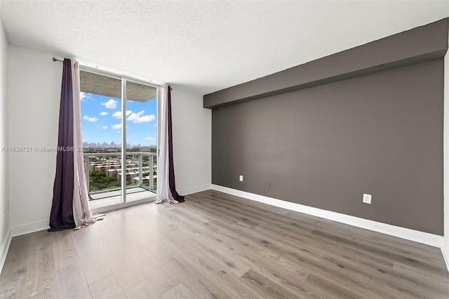 5077 NW 7th St Unit Ph15, Miami, FL 33126 - spare room featuring a wall of windows, wood finished floors, and a textured ceiling