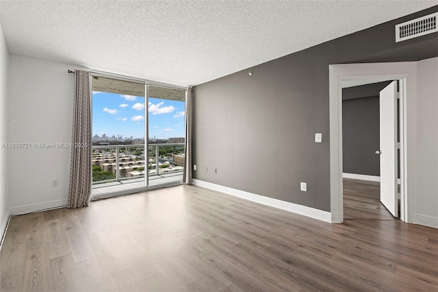 5077 NW 7th St Unit Ph15, Miami, FL 33126 - spare room featuring wood finished floors, a textured ceiling, a wall of windows, and a view of city