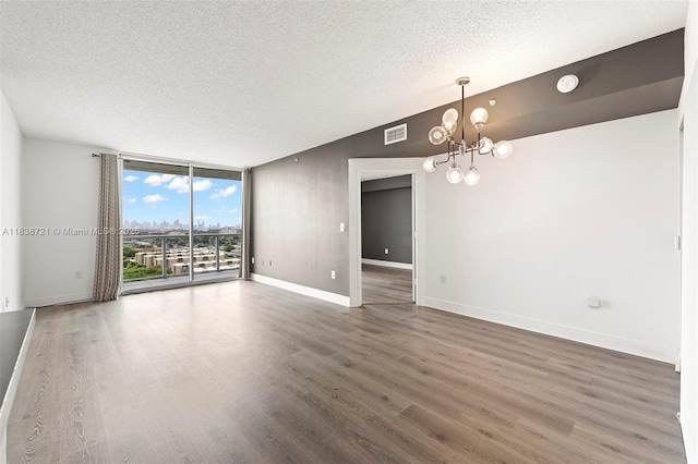 5077 NW 7th St Unit Ph15, Miami, FL 33126 - unfurnished room with a textured ceiling, a chandelier, wood finished floors, a smoke detector, and a wall of windows