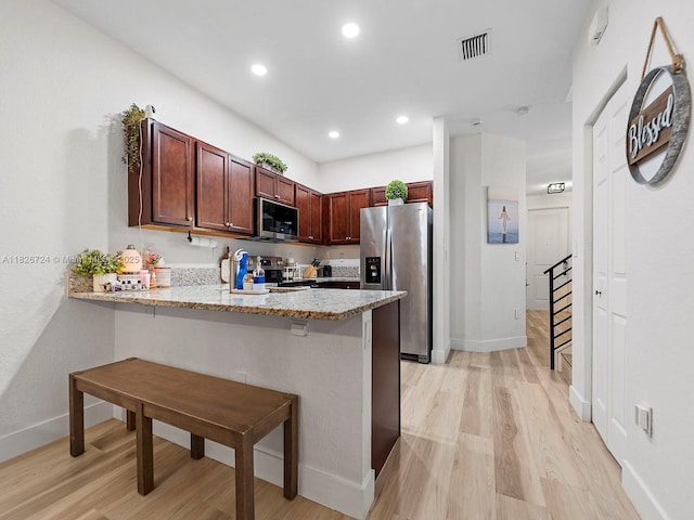 11901 SW 150th Pl, Miami, FL 33196 - kitchen featuring appliances with stainless steel finishes, a peninsula, light wood finished floors, a kitchen breakfast bar, and light stone countertops