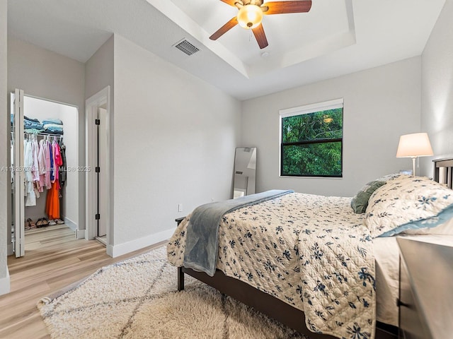 11901 SW 150th Pl, Miami, FL 33196 - bedroom featuring light wood finished floors, a tray ceiling, a walk in closet, and a ceiling fan