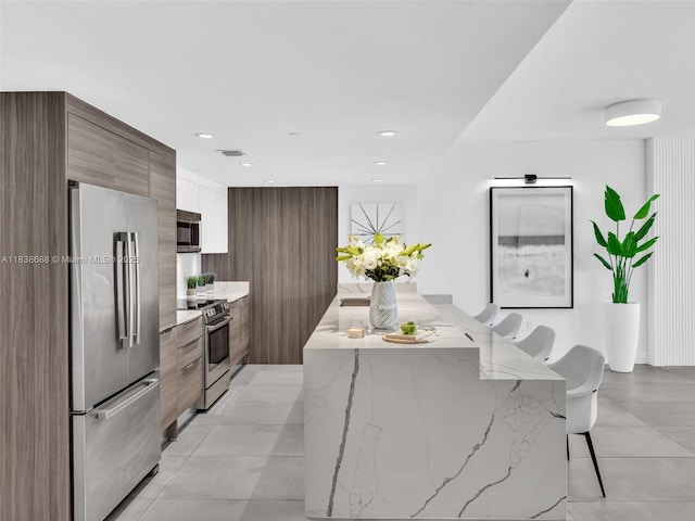9940 W Bay Harbor Dr Unit 3G-S, Bay Harbor Islands, FL 33154 - kitchen with appliances with stainless steel finishes, modern cabinets, a breakfast bar area, a kitchen island, and light stone countertops