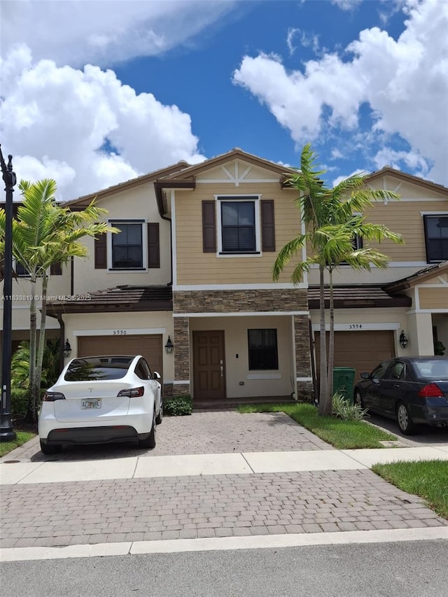 5990 Mustang Mnr, Davie, FL 33314 - view of front facade featuring stone siding, an attached garage, decorative driveway, and stucco siding