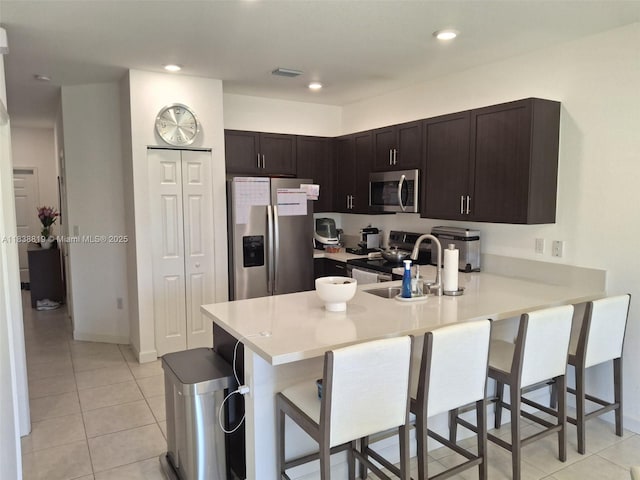 5990 Mustang Mnr, Davie, FL 33314 - kitchen featuring appliances with stainless steel finishes, a peninsula, a kitchen bar, light countertops, and light tile patterned floors