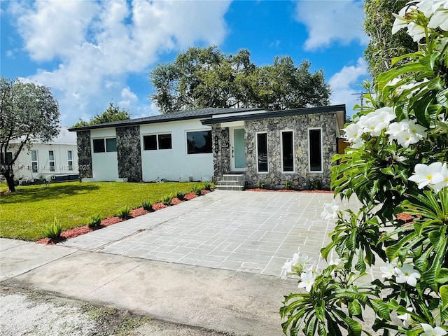 1930 NE 178th St, North Miami Beach, FL 33162 - view of front of house featuring stone siding, concrete driveway, and a front yard