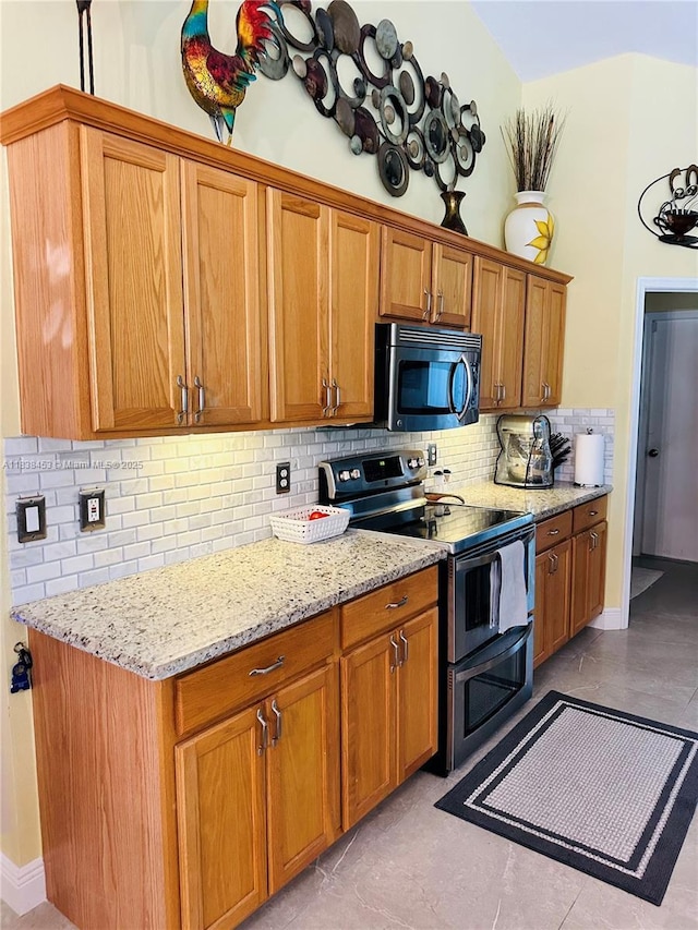 kitchen featuring appliances with stainless steel finishes, tasteful backsplash, light stone countertops, and brown cabinetry