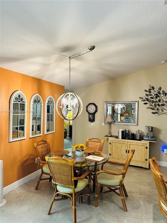 dining space featuring a chandelier and baseboards